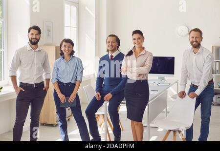 Jeunes professionnels ambitieux qui regardent des appareils photo et sourient réunion d'entreprise au bureau Banque D'Images