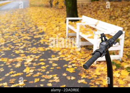 Un scooter devant un banc recouvert d'un feuillage d'automne jaune. Concept, repos, vacances, solitude. Photo de haute qualité Banque D'Images