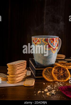 Tasse de thé à la vapeur avec des biscuits simples et des tranches d'orange séchées. Banque D'Images