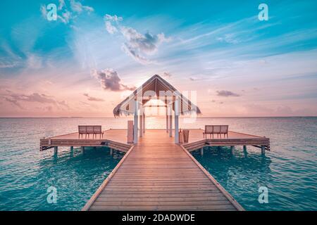 Coucher de soleil sur l'île des Maldives, complexe de villas de luxe sur l'eau et jetée en bois. Magnifique ciel et nuages et plage. Vacances d'été incroyables, vue de détente Banque D'Images