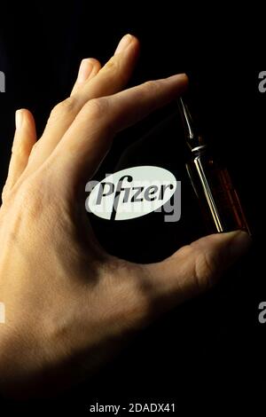 Société pharmaceutique Pfizer de vaccins contre le coronavirus. Logo Pfizer avec vaccin à main. Banque D'Images