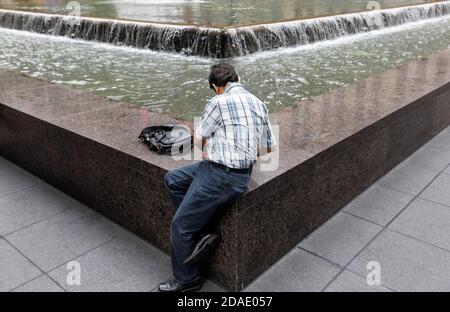 NEW YORK, États-Unis - 18 septembre 2017 : scène de rue de Manhattan. Américains dans les rues de New York. Un homme est assis près d'une fontaine sur la 6e Avenue de Manhattan Banque D'Images