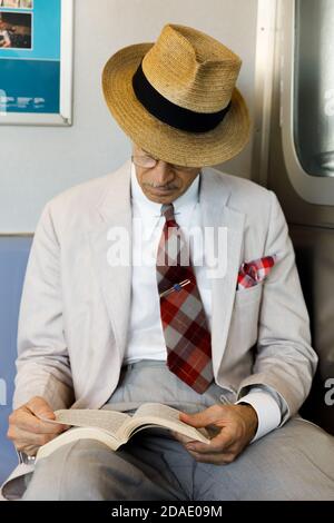 NEW YORK, États-Unis - 22 septembre 2017 : métro de la ville de New York. Un homme âgé en lunettes et un chapeau de paille lisant un livre dans une voiture de métro. Banque D'Images