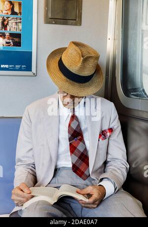 NEW YORK, États-Unis - 22 septembre 2017 : métro de la ville de New York. Un homme âgé en lunettes et un chapeau de paille lisant un livre dans une voiture de métro. Banque D'Images