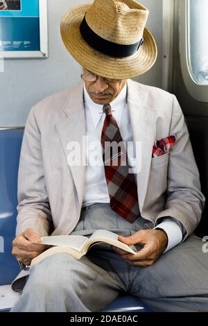 NEW YORK, États-Unis - 22 septembre 2017 : métro de la ville de New York. Un homme âgé en lunettes et un chapeau de paille lisant un livre dans une voiture de métro. Banque D'Images