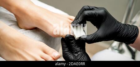 Mains de pédicuriste de polissage de la queue de crapaule de la femme par l'ongle blanc buff dans le salon de manucure Banque D'Images