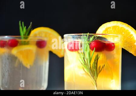 verres de cocktail de bourbon au miel avec boisson aigre au romarin et zeste d'orange, avec canneberges rouges ou boisson chaude d'hiver punch ou vin chaud Banque D'Images