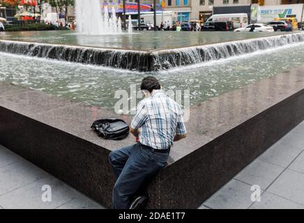 NEW YORK, États-Unis - 18 septembre 2017 : scène de rue de Manhattan. Américains dans les rues de New York. Un homme est assis près d'une fontaine sur la 6e Avenue de Manhattan Banque D'Images