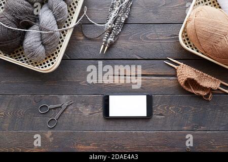 Vue en grand angle d'une table en bois avec panier et boules de laine et de téléphone portable sur elle Banque D'Images