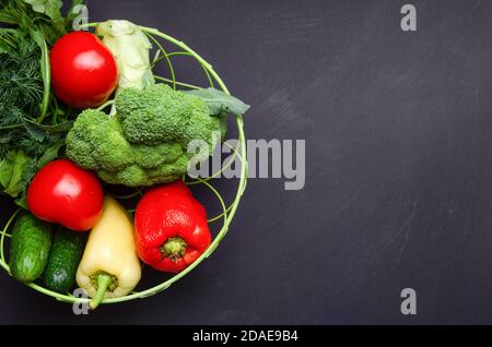 mélange végétal de tomates, concombres, herbes, brocoli, dans une assiette sur fond sombre. Espace libre pour le texte. Banque D'Images