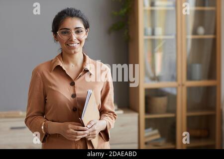 Portrait d'une jeune femme d'affaires en lunettes et en blouse dossiers et sourire à l'appareil photo au bureau Banque D'Images