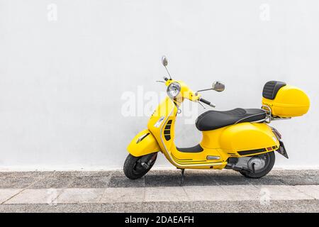 Scooter jaune dans une allée avec mur blanc, moto rétro, croisière en ville Banque D'Images