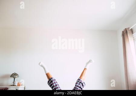 Chambre blanche à la maison dans la chambre et des gens fous jouer à l'intérieur - femme jambes et arrière-plan - matin réveil up concept pour une dame heureuse et joyeuse Banque D'Images