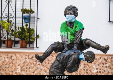 Statues de bronze de deux enfants jouant dans la rue sautant les uns sur les autres portant des masques faciaux Banque D'Images