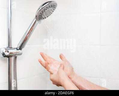 Gros plan des mains femelles avec mousse sous la douche Banque D'Images