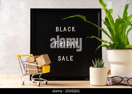 Texte Vendredi noir sur panneau de lettres noir, plantes, panier avec des boîtes sur fond en bois. Temps de vente de la saison concept. Modèle de mise en page pour votre de Banque D'Images