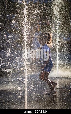 KIEV, UKRAINE - 05 juin 2018: Gaie et heureuse fille jouant dans une fontaine d'eau et appréciant les ruisseaux frais de l'eau dans une journée chaude. Été chaud. Banque D'Images