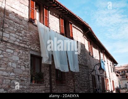 Draps suspendus pour sécher à l'extérieur de la fenêtre d'une ancienne maison en pierre dans un village médiéval italien (Gubbio, Ombrie, Italie, Europe) Banque D'Images