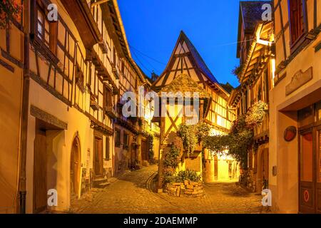 Scène nocturne le long de la rue de Remparts qui fait le tour du centre d'Eguisheim, un village médiéval magnifiquement préservé dans la région viticole d'Alsace en France. Banque D'Images