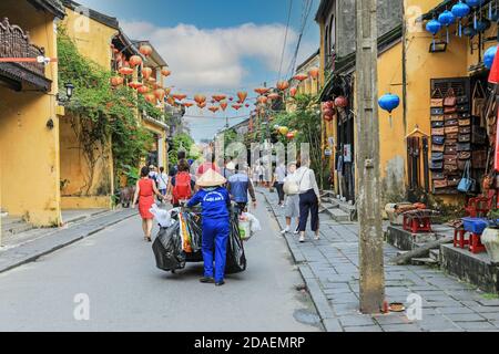 Une femme nettoyant de rue portant un chapeau conique vietnamien traditionnel dans une rue secondaire à Hoi an, Vietnam, Asie Banque D'Images