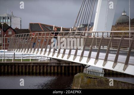 Port de plaisance de Swansea, Swansea, Royaume-Uni. 12 novembre 2020. Les gens traversent aujourd'hui la passerelle moderne qui relie les quais de Swansea à la marina de Swansea lors d'une pause dans le temps humide et venteux qui traverse le Royaume-Uni. Credit: Phil Rees/Alamy Live News Banque D'Images