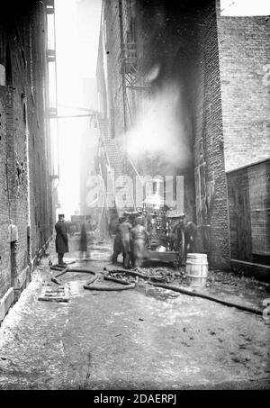 Vue d'un pompier et d'un pompier masculin dans une allée pendant l'incendie du théâtre Iroquois, 30 décembre 1903, Chicago, Illinois. Banque D'Images