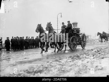 Test du conducteur de moteur d'incendie, homme conduisant un moteur d'incendie tiré par des chevaux dans une rue de ville Banque D'Images