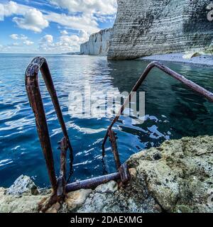 Échelle descendant dans la mer avec sur l'arrière-plan des falaises de calcaire à Etretat, côte française Banque D'Images