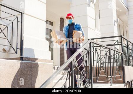 homme de livraison de nourriture avec des sacs dans un masque de protection son visage Banque D'Images