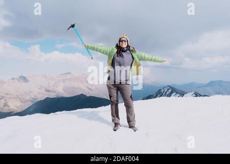 Bonne femme randonneur avec un brise-glace au sommet d'une montagne. Temps de neige. Banque D'Images