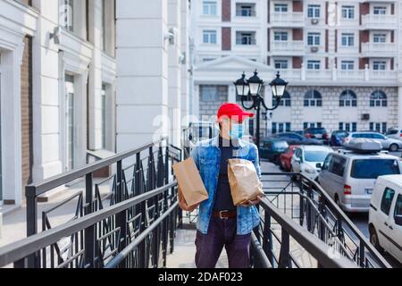 homme de livraison de nourriture avec des sacs dans un masque de protection son visage Banque D'Images