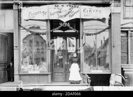 Femme debout à l'extérieur de M. K. Franz, vendant des bonbons, des jouets, des notions, des articles fixes et du tabac, 934 Lincoln Avenue, Chicago, Illinois, vers 1895. Banque D'Images