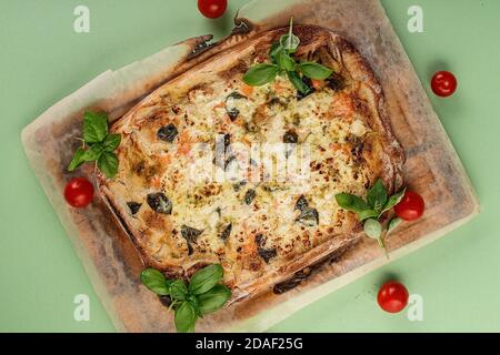 Croûte mince de pinsa avec du saumon fumé, du basilic et de la mozzarella sur fond vert. Cuisine italienne traditionnelle. Vue de dessus Banque D'Images