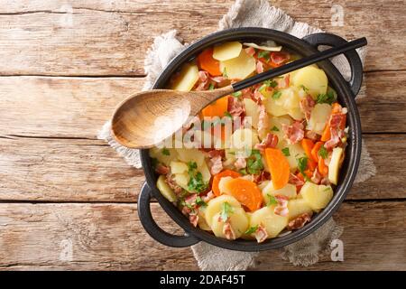 Ragoût de pommes de terre gallois avec du bacon, des oignons et des carottes en gros plan dans une poêle sur la table. Vue horizontale du dessus Banque D'Images