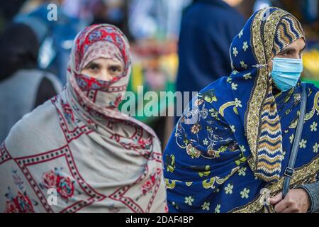 Londres, Royaume-Uni - 3 novembre 2020 - les femmes musulmanes d'Asie portent un masque facial (attention à droite) et un hijab comme couverture faciale pendant leurs achats à Walthamstow M. Banque D'Images