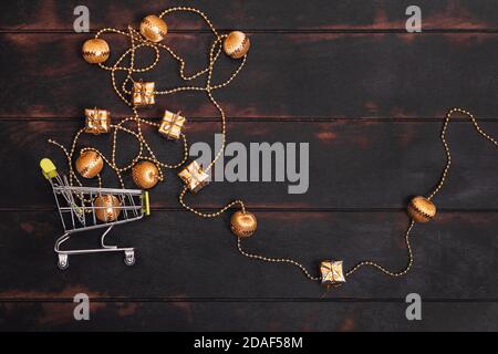 Petit panier avec cadeaux dorés sur fond de bois. Banque D'Images