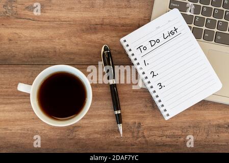 Liste des tâches sur le bloc-notes au-dessus de l'ordinateur portable avec une tasse de café et un stylo Banque D'Images