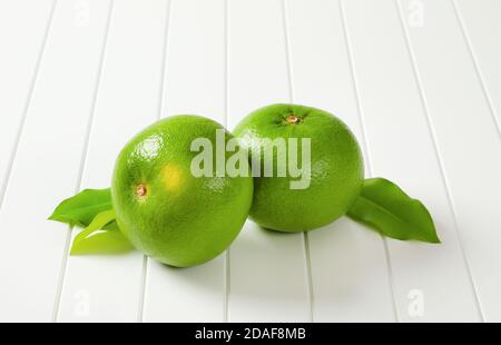 Deux fruits de l'amour entiers (fruits verts, pomelits) et des feuilles Banque D'Images