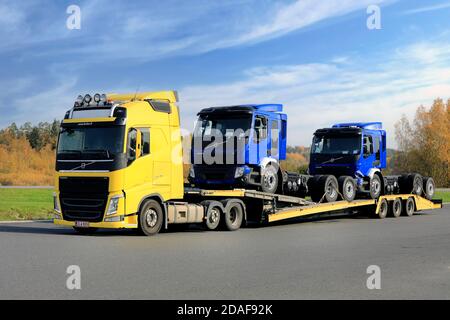 Le transporteur de véhicules Volvo FH jaune de Hulex Oy transporte deux nouveaux camions Volvo FE bleus à travers le chantier d'arrêt de camion. Forssa, Finlande. 2 octobre 2020. Banque D'Images