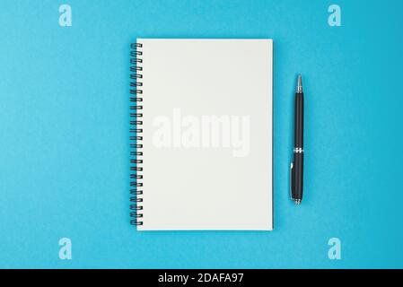 directement au-dessus de la vue du bloc-notes et de la pointe à bille à spirale vierges stylo sur fond bleu Banque D'Images