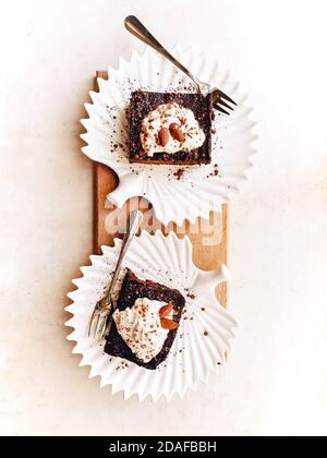 Deux délicieux desserts au chocolat paleo sur des assiettes de feuilles en porcelaine blanche. Alimentation sans gluten, brute et saine. Vue de dessus de la pose à plat Banque D'Images