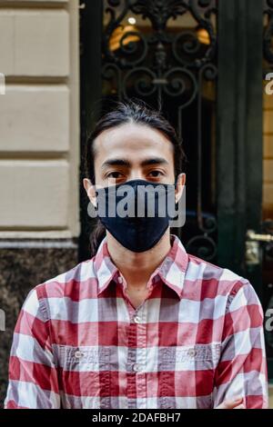 homme avec un masque et une chemise rouge devant d'une porte Banque D'Images