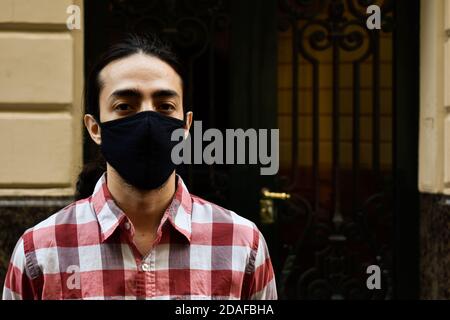 homme avec un masque et une chemise rouge devant d'une porte Banque D'Images