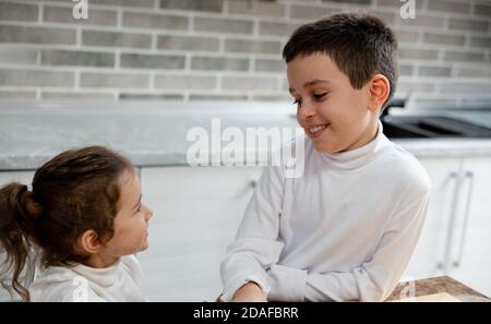 Le garçon et une fille se sourient. Les enfants cuisinent dans leur cuisine. Banque D'Images