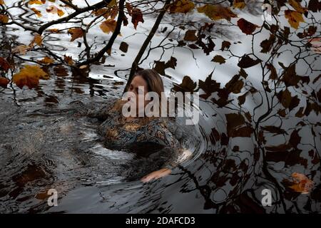 Dame portant une robe, à l'intérieur de l'eau en un jour d'automne Banque D'Images