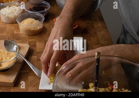 Homme tenant une assiette de saumon et de salade Couscous une table en bois Banque D'Images