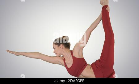 Professeur de yoga pratiquant pose dandayamana dhanurasana sur gradient Banque D'Images