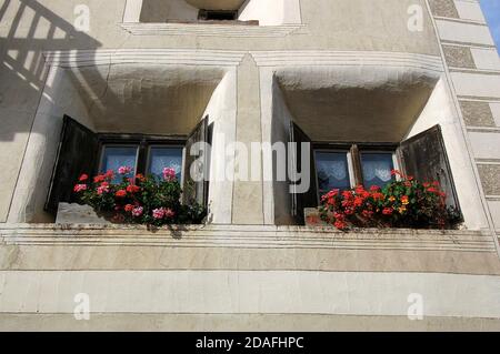 Fenêtres avec fleurs en pot et décorations dans l'ancien village d'Ardez, commune de Scuol, vallée d'Engadin, canton de Graubunden, Suisse, Europe. Banque D'Images