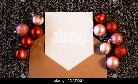 Feuille de papier vierge pour notes, enveloppe en papier kraft sur fond tricoté foncé. Le concept de la nouvelle année. Copier l'espace pour le texte Banque D'Images