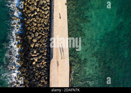 Vue aérienne de deux personnes jetant de longues ombres sur la passerelle vers le phare de la ville de Chania, Crète, Grèce Banque D'Images